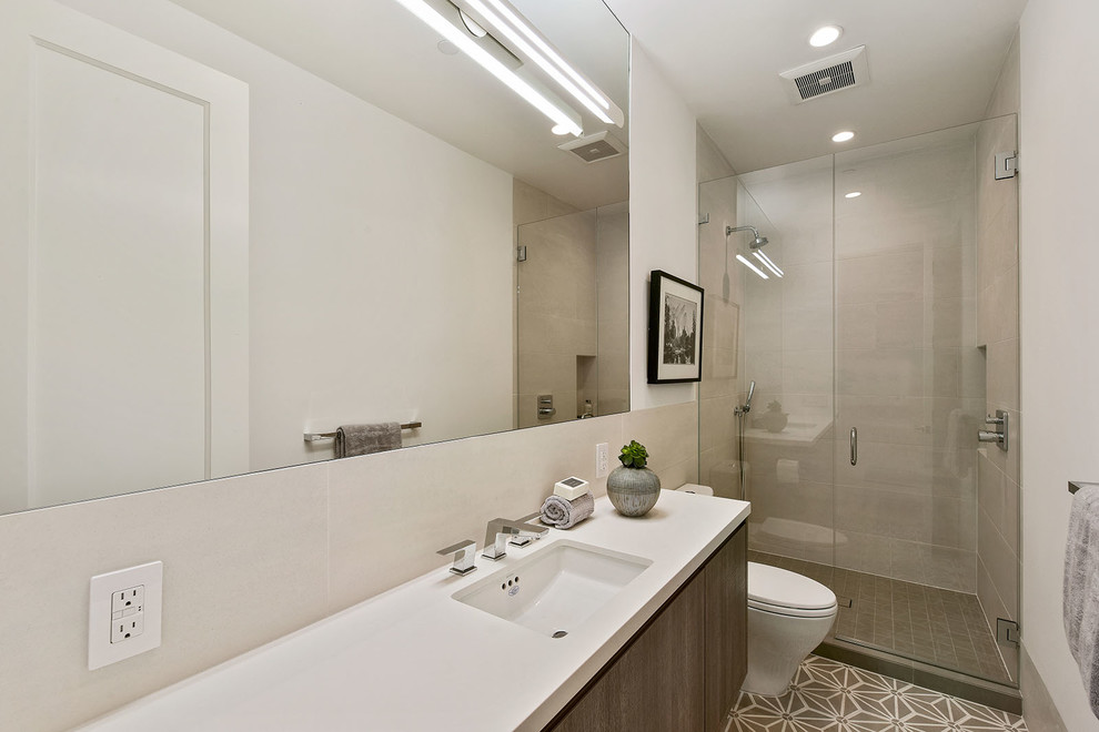 Contemporary shower room bathroom in San Francisco with flat-panel cabinets, medium wood cabinets, an alcove shower, a one-piece toilet, beige tiles, beige walls, cement flooring, a submerged sink, beige floors and a hinged door.