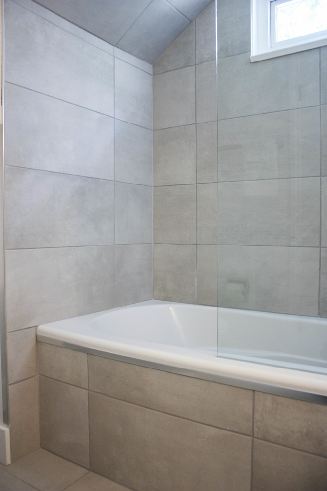 Стильный дизайн: детская ванная комната среднего размера в стиле модернизм с плоскими фасадами, белыми фасадами, ванной в нише, душем над ванной, унитазом-моноблоком, серой плиткой, керамической плиткой, серыми стенами, полом из керамической плитки, врезной раковиной, столешницей из бетона, серым полом и открытым душем - последний тренд