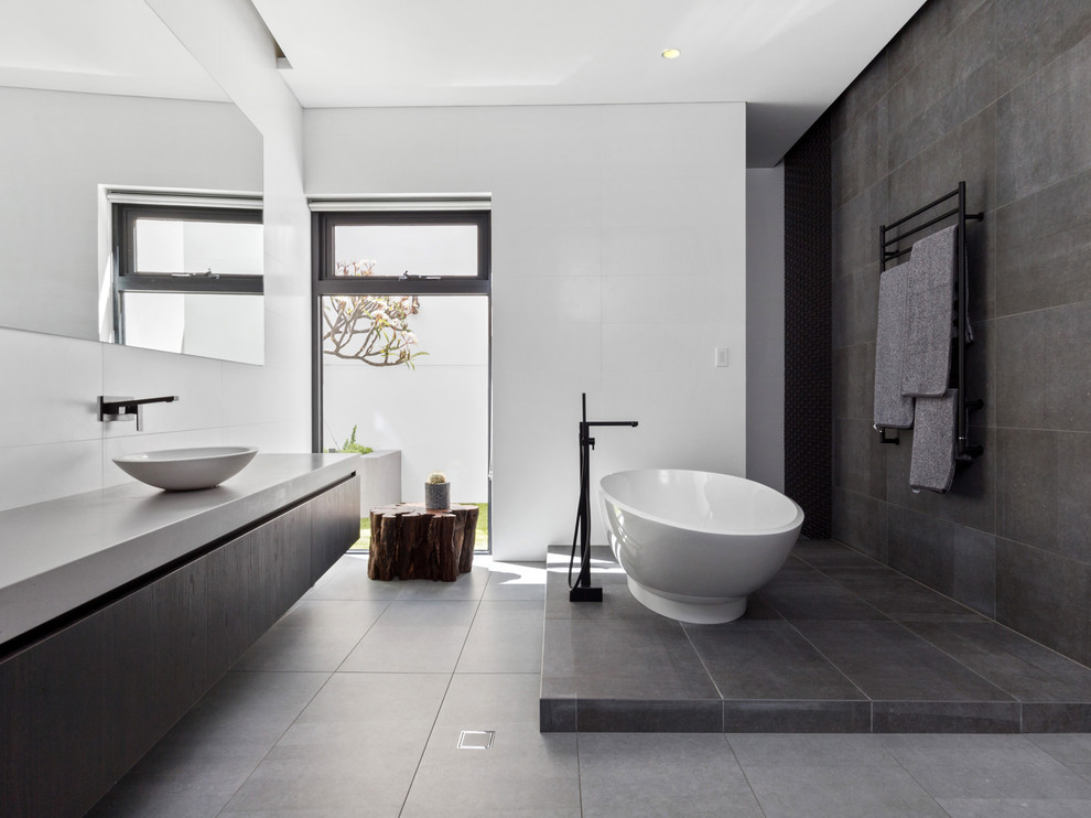 Идея дизайна: главная ванная комната в современном стиле с плоскими фасадами, серыми фасадами, отдельно стоящей ванной, серой плиткой, белыми стенами, настольной раковиной, серым полом и серой столешницей