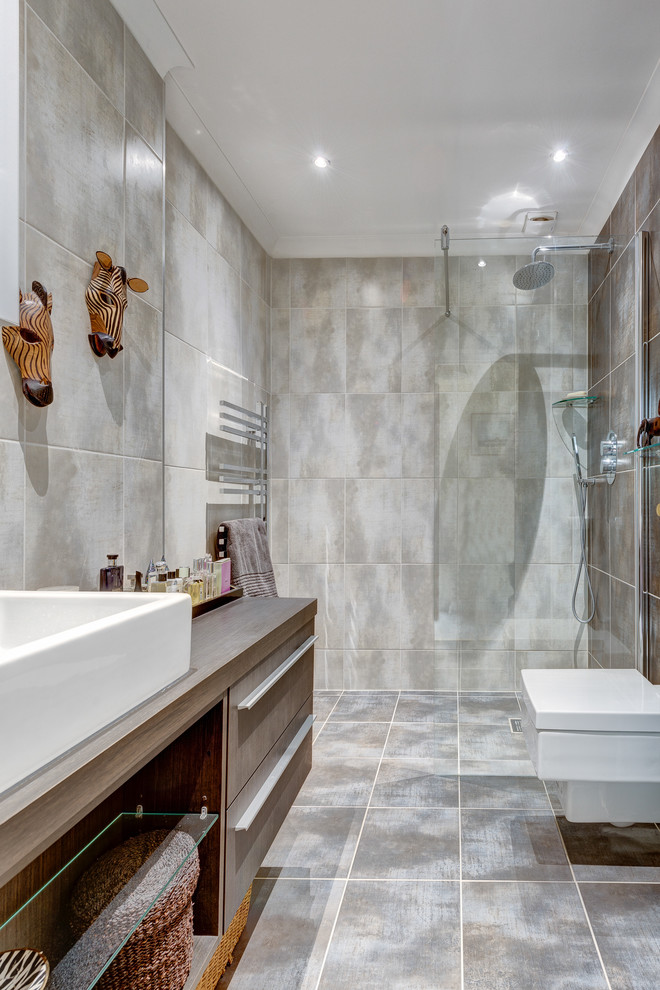 Cette image montre une salle de bain traditionnelle en bois foncé de taille moyenne avec un placard en trompe-l'oeil, un plan de toilette en bois, une douche à l'italienne, WC suspendus, un carrelage gris, des carreaux de céramique, un mur gris et un sol en carrelage de céramique.