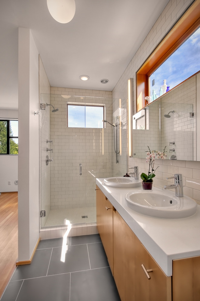 Modernes Badezimmer mit Einbauwaschbecken, flächenbündigen Schrankfronten, hellbraunen Holzschränken, Duschnische, weißen Fliesen, Metrofliesen und grauem Boden in Seattle