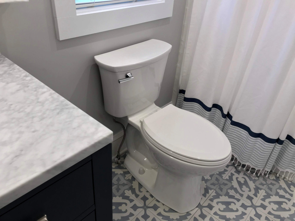 Bild på ett mycket stort maritimt grå grått badrum för barn, med skåp i shakerstil, en toalettstol med separat cisternkåpa, vit kakel, porslinskakel, grå väggar, ett undermonterad handfat, bänkskiva i kvarts, klinkergolv i porslin, blå skåp, en dusch/badkar-kombination, blått golv och dusch med duschdraperi