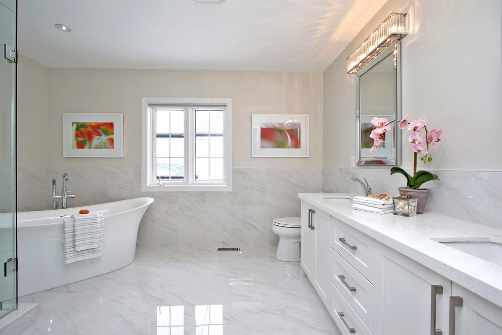 Пример оригинального дизайна: главная ванная комната среднего размера в стиле неоклассика (современная классика) с фасадами с утопленной филенкой, белыми фасадами, отдельно стоящей ванной, угловым душем, бежевыми стенами, мраморным полом, врезной раковиной, столешницей из искусственного кварца, белым полом и душем с распашными дверями