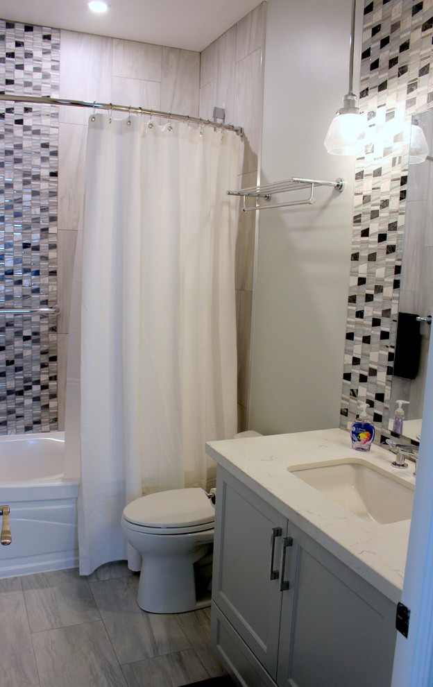 Exempel på ett mellanstort modernt vit vitt badrum för barn, med skåp i shakerstil, grå skåp, ett badkar i en alkov, en dusch/badkar-kombination, en toalettstol med separat cisternkåpa, svart och vit kakel, marmorkakel, grå väggar, klinkergolv i porslin, ett undermonterad handfat, bänkskiva i kvarts, grått golv och dusch med duschdraperi