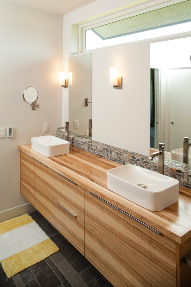 オマハにあるコンテンポラリースタイルのおしゃれな浴室 (ベッセル式洗面器、淡色木目調キャビネット、木製洗面台、グレーのタイル) の写真