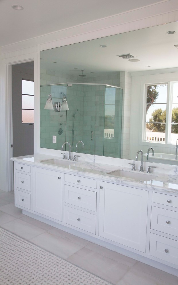 Large beach style ensuite bathroom in Los Angeles with a submerged sink, shaker cabinets, white cabinets, marble worktops, a freestanding bath, a corner shower, a one-piece toilet, white tiles, stone tiles, white walls and marble flooring.