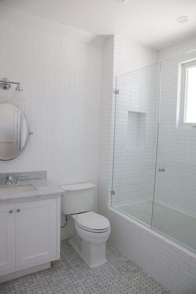 Photo of a large beach style bathroom in Los Angeles with a submerged sink, shaker cabinets, white cabinets, marble worktops, a submerged bath, a corner shower, a two-piece toilet, white tiles, metro tiles, white walls and marble flooring.