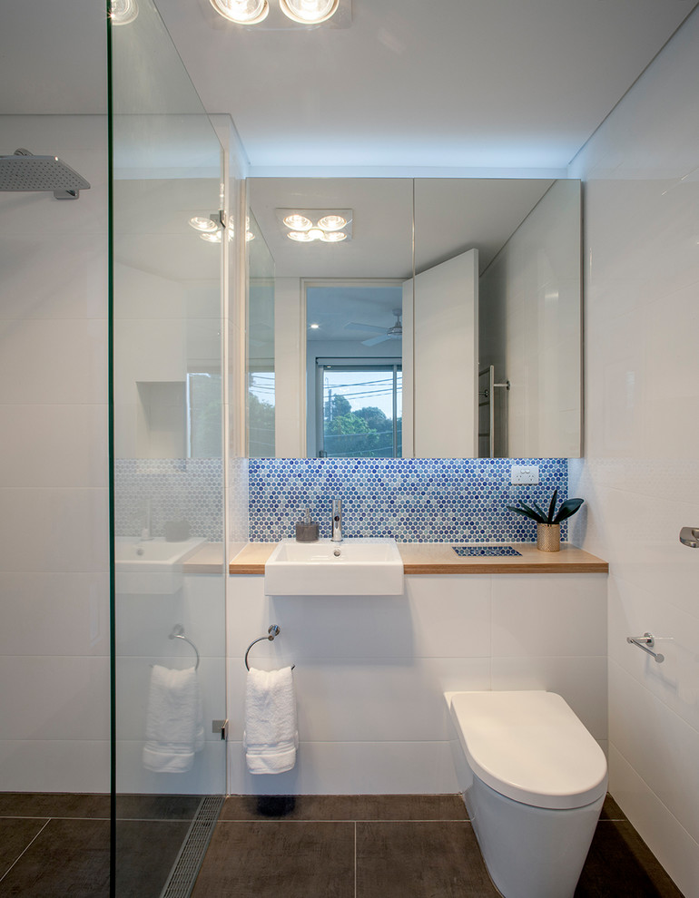 シドニーにあるコンテンポラリースタイルのおしゃれなバスルーム (浴槽なし) (バリアフリー、壁掛け式トイレ、白い壁、オーバーカウンターシンク、木製洗面台、黒い床、オープンシャワー、ブラウンの洗面カウンター) の写真