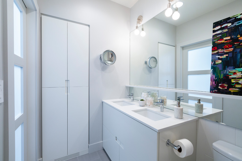 This is an example of a medium sized modern shower room bathroom in Denver with a one-piece toilet, grey walls, porcelain flooring, grey floors, a submerged sink, flat-panel cabinets, white cabinets, an alcove bath, a shower/bath combination, solid surface worktops, white worktops, white tiles, ceramic tiles and a shower curtain.