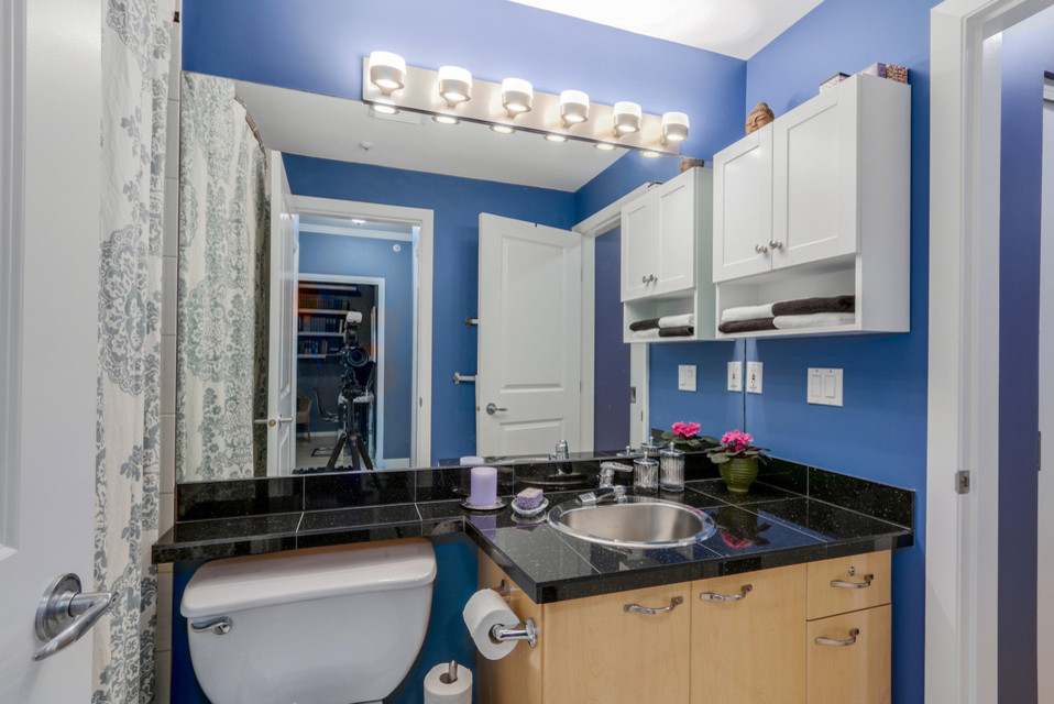 Kleines Modernes Badezimmer mit flächenbündigen Schrankfronten, hellen Holzschränken, Badewanne in Nische, Duschbadewanne, Toilette mit Aufsatzspülkasten, weißen Fliesen, Keramikfliesen, blauer Wandfarbe, Einbauwaschbecken und Duschvorhang-Duschabtrennung in Vancouver