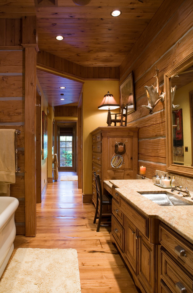 Example of a mid-sized mountain style master light wood floor bathroom design in Other with furniture-like cabinets, medium tone wood cabinets, an undermount sink, granite countertops and beige countertops