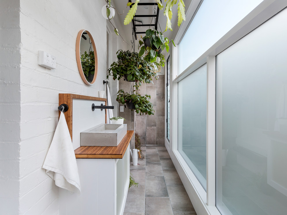 Immagine di una stretta e lunga stanza da bagno tradizionale con ante bianche, pareti bianche, lavabo a bacinella, top in legno e top marrone