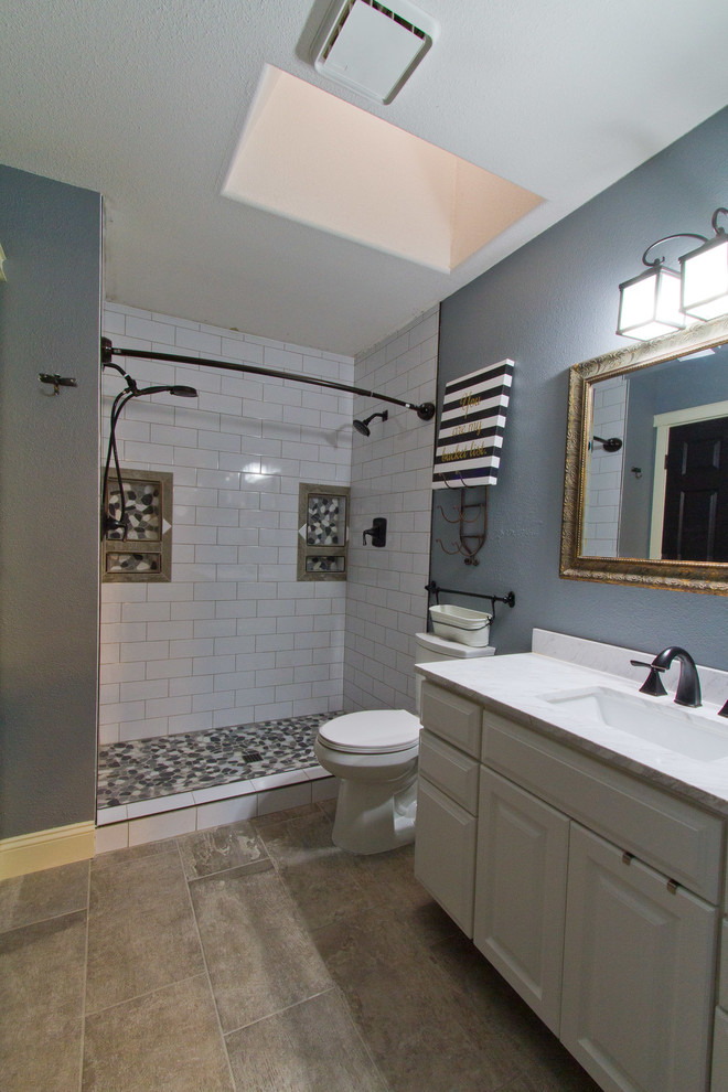 Example of a transitional gray tile, white tile and pebble tile porcelain tile alcove shower design in Denver with raised-panel cabinets, white cabinets, gray walls, an undermount sink and marble countertops