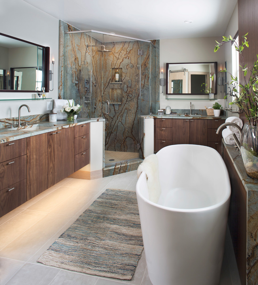 Идея дизайна: главная ванная комната в современном стиле с плоскими фасадами, темными деревянными фасадами, отдельно стоящей ванной, угловым душем, разноцветной плиткой, плиткой из листового камня, серыми стенами, врезной раковиной, бежевым полом, душем с распашными дверями, разноцветной столешницей и зеркалом с подсветкой