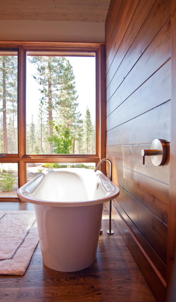 Bild på ett rustikt badrum, med ett fristående badkar, beige väggar och mellanmörkt trägolv