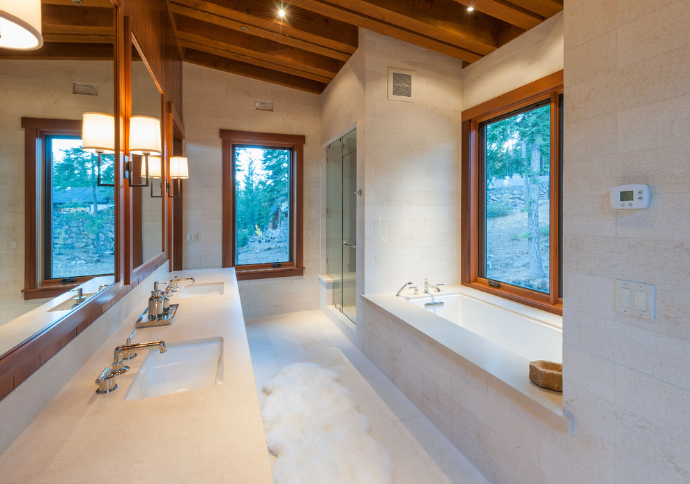 Exemple d'une douche en alcôve tendance avec un lavabo encastré, une baignoire encastrée, un carrelage beige et un mur en pierre.