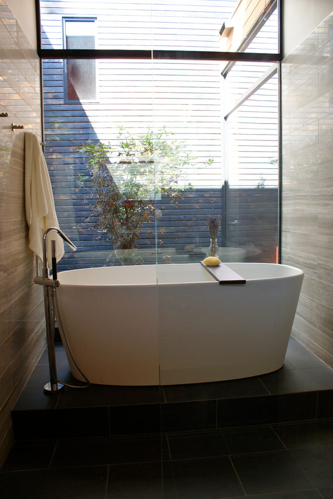 На фото: главная ванная комната в стиле модернизм с плоскими фасадами, темными деревянными фасадами, столешницей из искусственного кварца, отдельно стоящей ванной, черной плиткой и керамогранитной плиткой