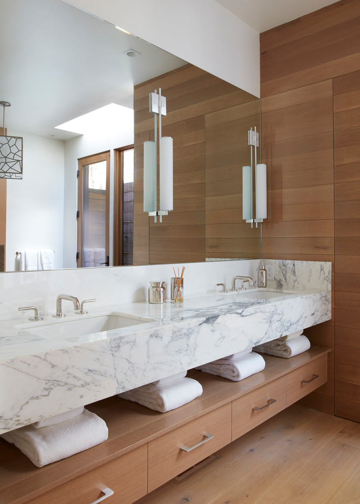 Cette photo montre une salle de bain principale tendance en bois brun de taille moyenne avec un placard à porte plane, un mur marron, un sol en bois brun, un lavabo encastré, un plan de toilette en marbre et un sol marron.