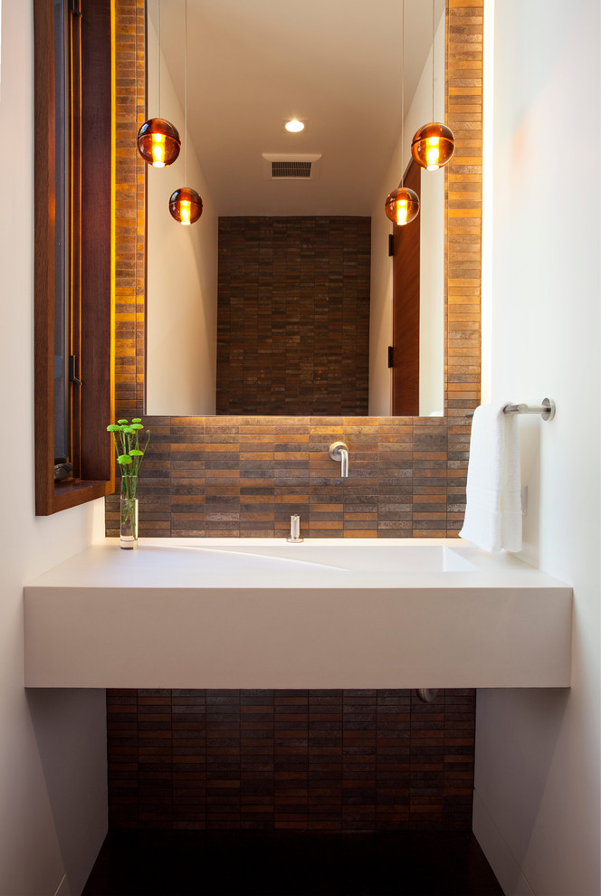 Cette photo montre une salle d'eau moderne de taille moyenne avec un lavabo intégré, WC à poser, des carreaux de porcelaine, un mur blanc et sol en béton ciré.