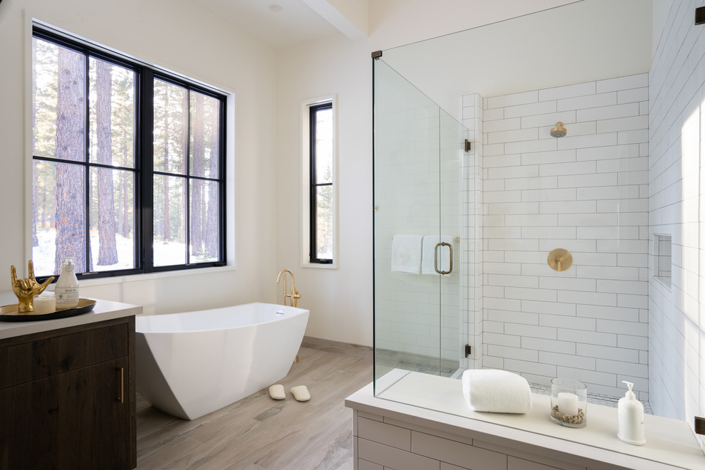 Inspiration for a large country master white tile and subway tile porcelain tile and gray floor freestanding bathtub remodel in Other with flat-panel cabinets, distressed cabinets, a one-piece toilet, white walls, an undermount sink, quartz countertops, a hinged shower door and white countertops