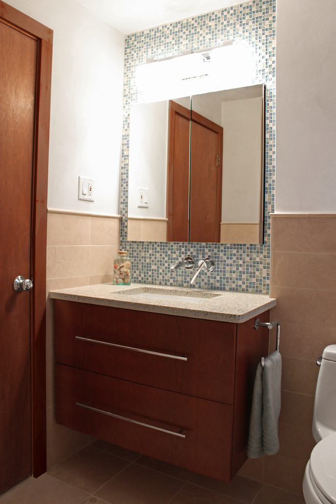 Cette image montre une petite salle de bain principale minimaliste en bois brun avec un lavabo encastré, un placard à porte plane, un plan de toilette en verre recyclé, une baignoire posée, un combiné douche/baignoire, WC à poser, un carrelage bleu, mosaïque, un mur blanc et un sol en marbre.