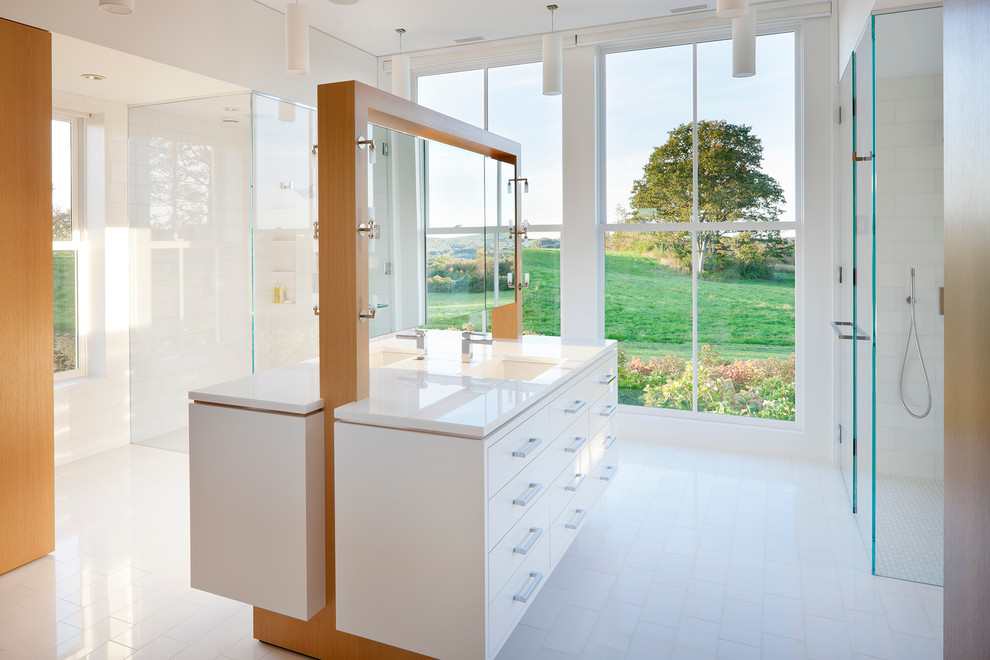 Cette image montre une salle de bain design avec un placard à porte plane, des portes de placard blanches, une douche d'angle, un carrelage blanc, un mur blanc et un lavabo encastré.