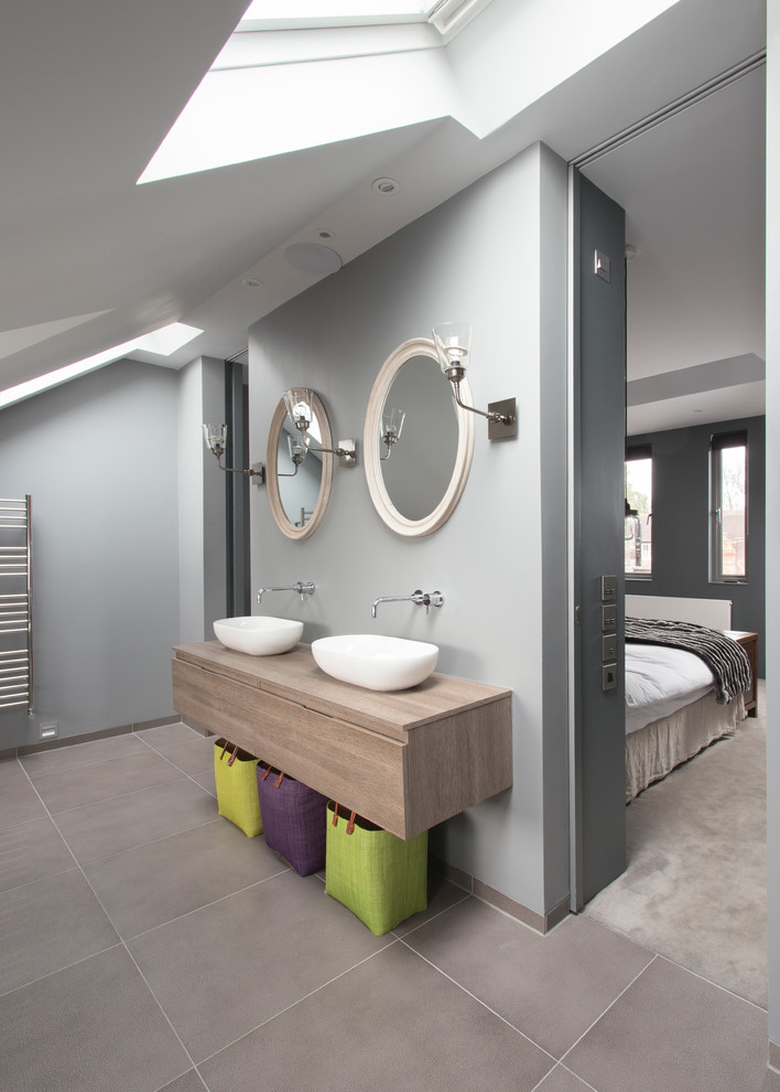 ロンドンにあるコンテンポラリースタイルのおしゃれなマスターバスルーム (フラットパネル扉のキャビネット、淡色木目調キャビネット、グレーの壁、ベッセル式洗面器、木製洗面台、ベージュの床、ベージュのカウンター) の写真