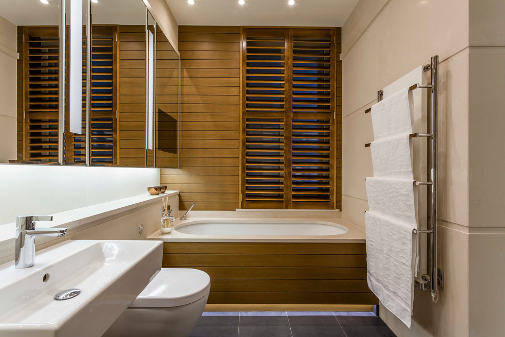 Inspiration för ett funkis badrum, med ett väggmonterat handfat, ett undermonterat badkar och en vägghängd toalettstol
