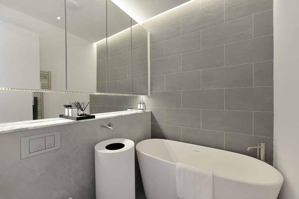 Inspiration för små moderna badrum, med luckor med glaspanel, ett fristående badkar, en öppen dusch, en toalettstol med hel cisternkåpa, grå kakel, stenkakel, grå väggar, ett piedestal handfat och marmorbänkskiva