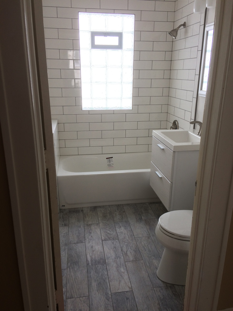 Small ensuite bathroom in Minneapolis with flat-panel cabinets, white cabinets, an alcove bath, an alcove shower, a two-piece toilet, white tiles, metro tiles, wood-effect flooring, an integrated sink, grey floors, a shower curtain, a single sink and a floating vanity unit.