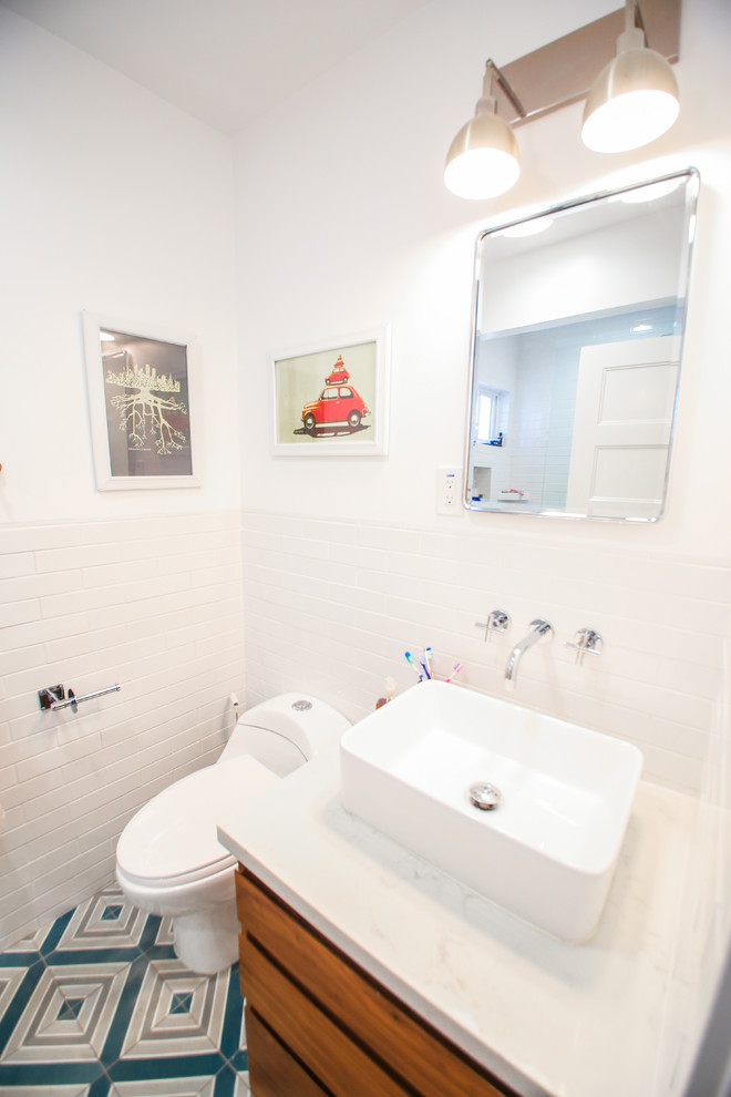 Bild på ett litet funkis vit vitt badrum, med skåp i mellenmörkt trä, ett fristående badkar, en dusch i en alkov, en toalettstol med hel cisternkåpa, vit kakel, tunnelbanekakel, vita väggar, klinkergolv i keramik, ett fristående handfat, bänkskiva i kvartsit, turkost golv och dusch med skjutdörr