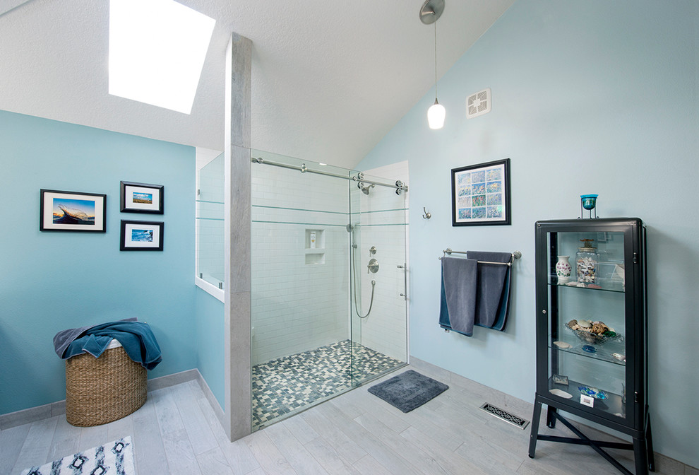 Example of a large beach style 3/4 white tile and subway tile light wood floor, gray floor and double-sink corner shower design in Portland with blue walls, a hinged shower door, shaker cabinets, blue cabinets, an undermount sink, marble countertops, a two-piece toilet, gray countertops, a niche and a built-in vanity