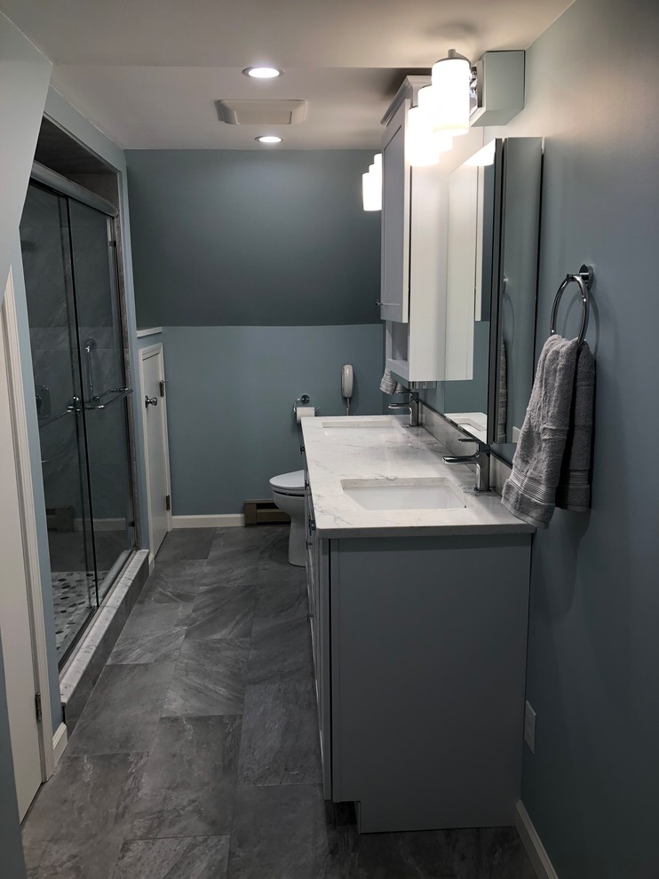 Photo of a medium sized classic ensuite bathroom in Burlington with raised-panel cabinets, grey cabinets, a double shower, a bidet, grey tiles, porcelain tiles, blue walls, porcelain flooring, a submerged sink, engineered stone worktops, grey floors, a sliding door and white worktops.