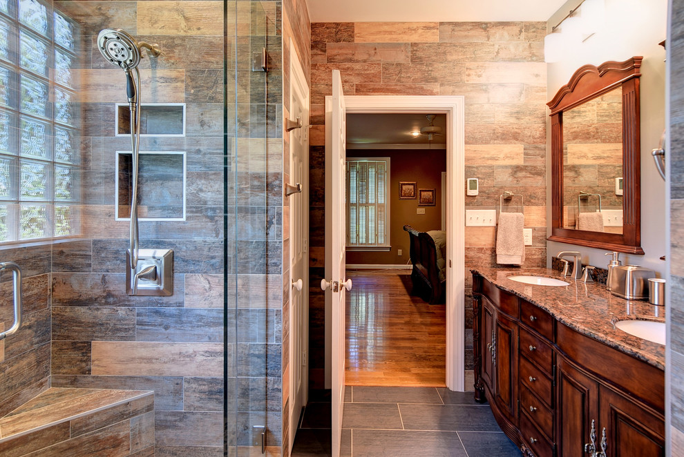 Mid-sized mountain style master brown tile slate floor and gray floor corner shower photo in Other with an undermount sink, dark wood cabinets, raised-panel cabinets, brown walls, granite countertops and a hinged shower door