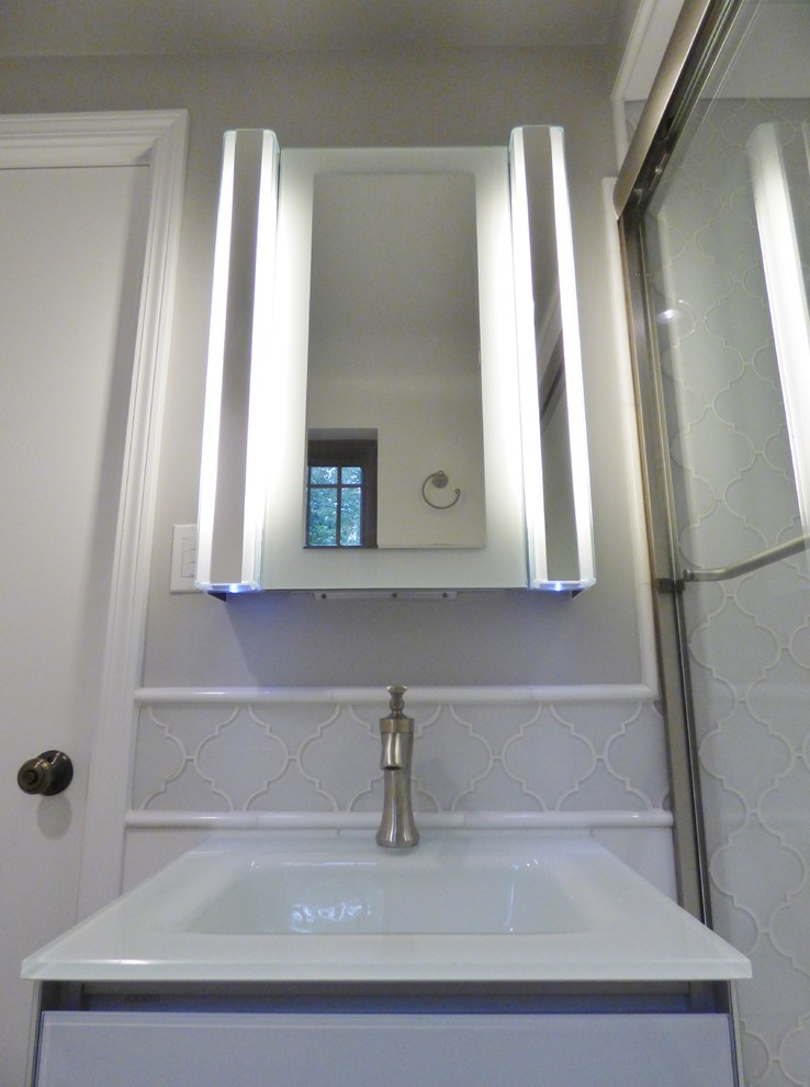 На фото: маленькая главная ванная комната в классическом стиле с плоскими фасадами, белыми фасадами, накладной ванной, душем над ванной, унитазом-моноблоком, серой плиткой, стеклянной плиткой, бежевыми стенами, полом из керамогранита, накладной раковиной, стеклянной столешницей, разноцветным полом и душем с раздвижными дверями для на участке и в саду