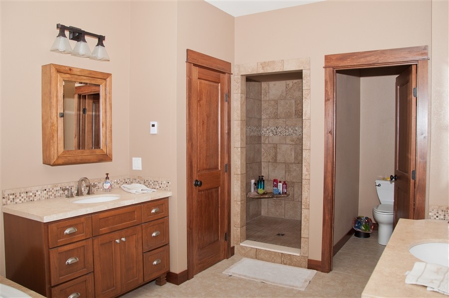 Idéer för ett mellanstort amerikanskt en-suite badrum, med skåp i mellenmörkt trä, beige kakel, keramikplattor, luckor med infälld panel, en hörndusch, beige väggar, klinkergolv i keramik, ett undermonterad handfat, laminatbänkskiva, beiget golv och med dusch som är öppen