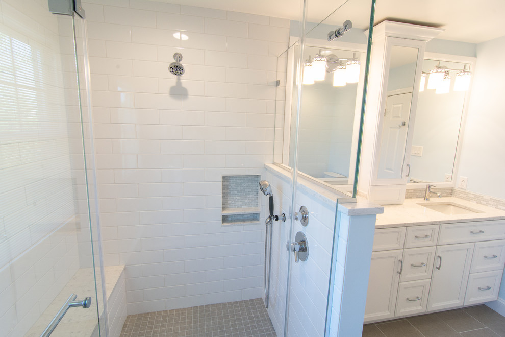 На фото: главная ванная комната среднего размера в стиле неоклассика (современная классика) с плоскими фасадами, белыми фасадами, угловым душем, раздельным унитазом, белой плиткой, керамической плиткой, синими стенами, полом из керамогранита, врезной раковиной, столешницей из искусственного кварца, серым полом, душем с распашными дверями и белой столешницей