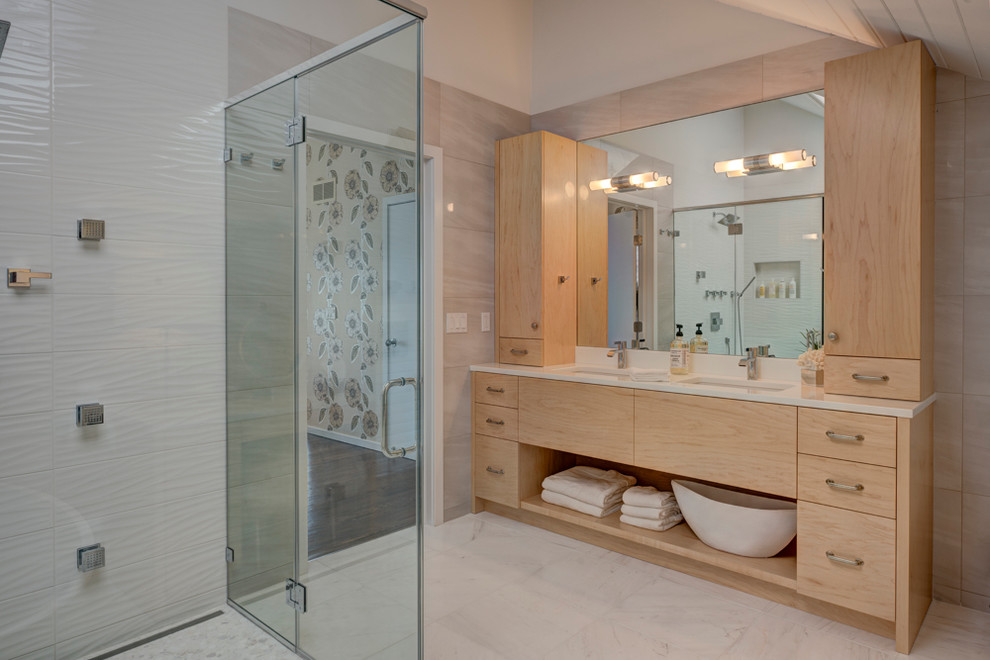 Exemple d'une salle de bain principale tendance en bois clair de taille moyenne avec un placard à porte plane, un carrelage blanc, des carreaux de porcelaine, un mur beige, un lavabo encastré et une cabine de douche à porte battante.
