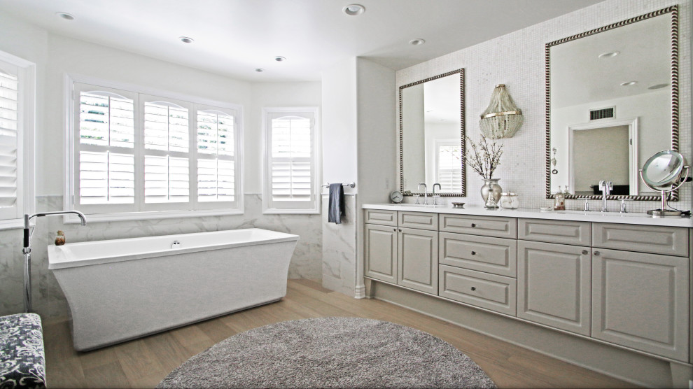 Idéer för mellanstora funkis vitt en-suite badrum, med släta luckor, grå skåp, ett fristående badkar, en toalettstol med hel cisternkåpa, grå kakel, glasskiva, vita väggar, ett nedsänkt handfat och brunt golv