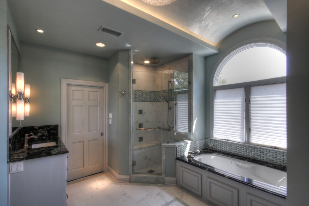 Large trendy master white tile and stone tile porcelain tile bathroom photo in Austin with an undermount sink, raised-panel cabinets, white cabinets, granite countertops, an undermount tub and blue walls