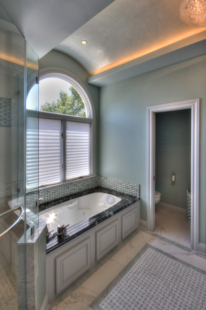 Inspiration pour une grande salle de bain principale design avec un placard avec porte à panneau surélevé, des portes de placard blanches, un plan de toilette en granite, une baignoire encastrée, un carrelage blanc, un carrelage de pierre, un mur bleu et un sol en carrelage de porcelaine.