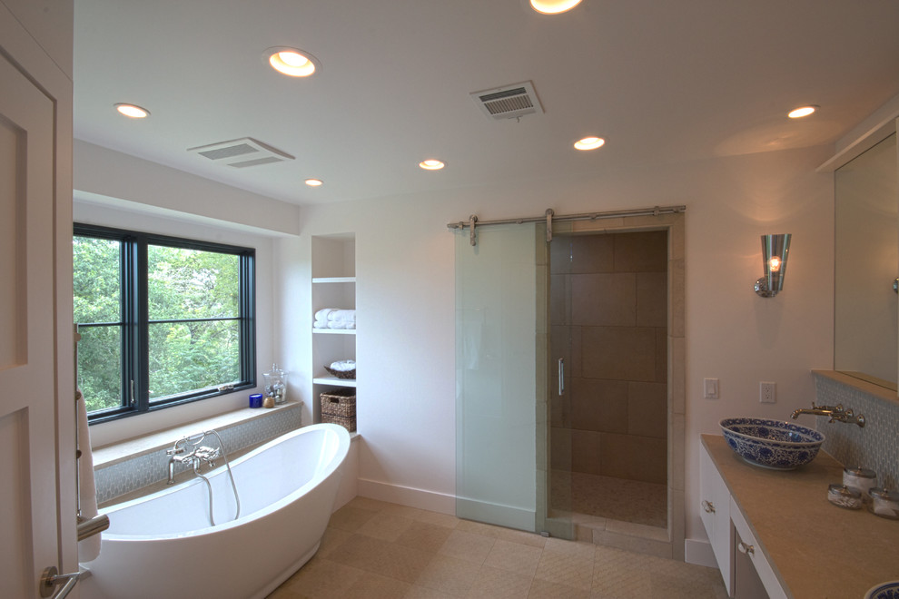 Inspiration for a medium sized contemporary sauna bathroom in Austin with a vessel sink, flat-panel cabinets, white cabinets, limestone worktops, a freestanding bath, white walls, limestone flooring, grey tiles and glass tiles.