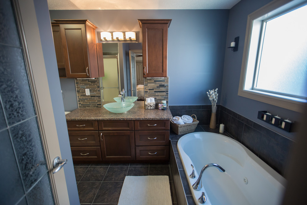Modernes Badezimmer En Suite mit Schrankfronten mit vertiefter Füllung, dunklen Holzschränken, Whirlpool, beigen Fliesen, blauer Wandfarbe, Aufsatzwaschbecken, Laminat-Waschtisch und grauem Boden in Sonstige