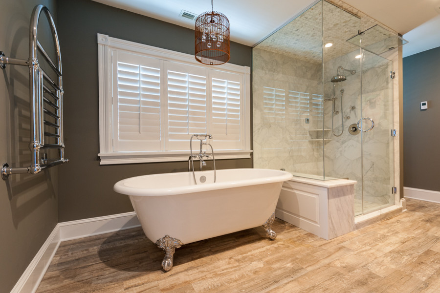 Exemple d'une salle de bain principale moderne de taille moyenne avec une douche d'angle, du carrelage en marbre, un mur marron, un sol en bois brun, une cabine de douche à porte battante et une baignoire sur pieds.