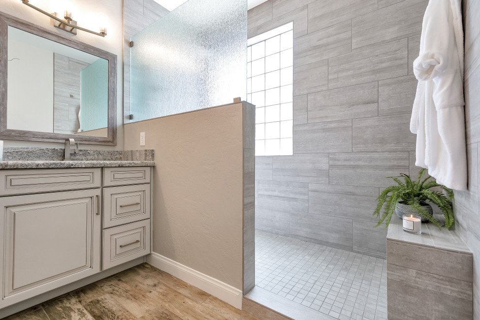 Идея дизайна: главная ванная комната среднего размера в стиле неоклассика (современная классика) с фасадами с выступающей филенкой, серыми фасадами, открытым душем, серой плиткой, керамогранитной плиткой, серыми стенами, полом из керамогранита, врезной раковиной, столешницей из гранита, серым полом, открытым душем, серой столешницей, сиденьем для душа, тумбой под две раковины и встроенной тумбой