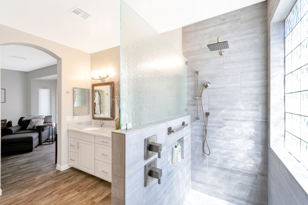 This is an example of a medium sized classic ensuite bathroom in Phoenix with raised-panel cabinets, grey cabinets, a walk-in shower, grey tiles, porcelain tiles, grey walls, porcelain flooring, a submerged sink, granite worktops, grey floors, an open shower, grey worktops, a shower bench, double sinks and a built in vanity unit.