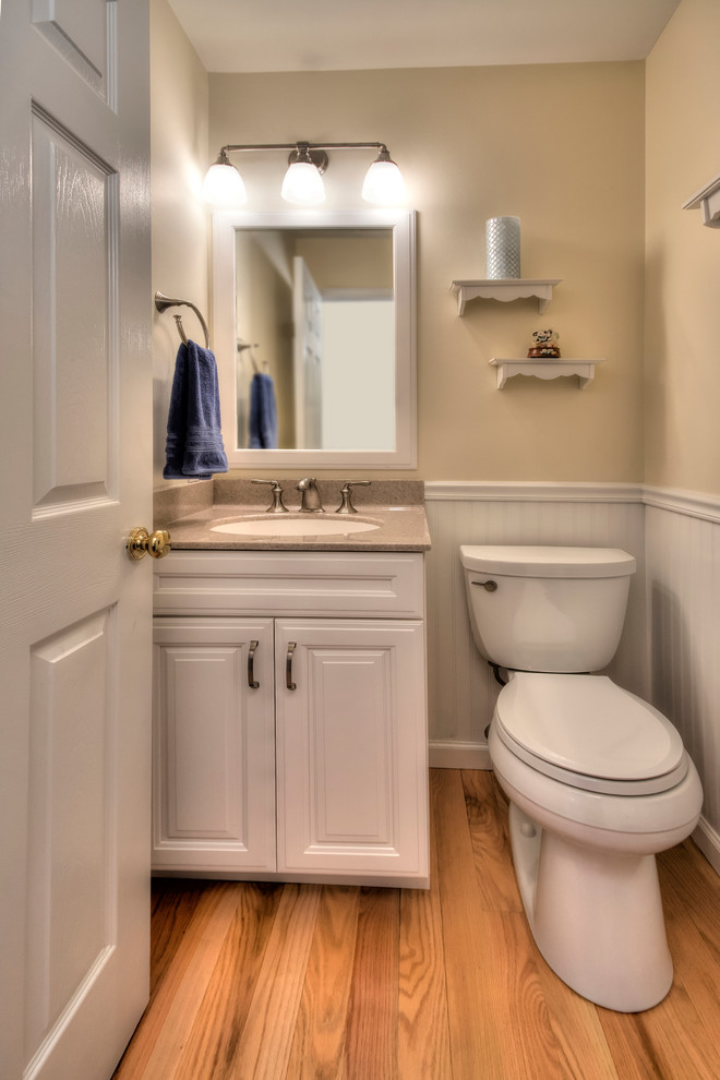 Diseño de cuarto de baño moderno con puertas de armario blancas, encimera de ónix, paredes beige y suelo de madera clara