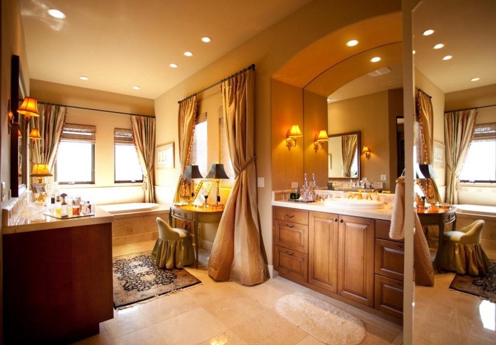 Imagen de cuarto de baño tradicional con lavabo sobreencimera, armarios con paneles con relieve, puertas de armario de madera oscura, bañera encastrada y baldosas y/o azulejos beige