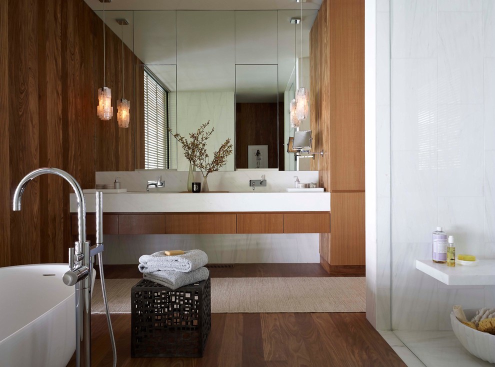 Cette photo montre une salle de bain moderne avec des portes de placard blanches, une baignoire indépendante, un carrelage blanc, un lavabo intégré et aucune cabine.