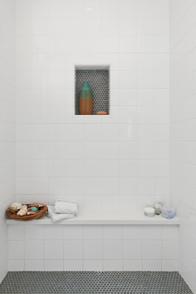 Aménagement d'une grande salle de bain principale bord de mer en bois foncé avec un placard à porte shaker, une baignoire indépendante, une douche d'angle, WC à poser, un carrelage bleu, un carrelage en pâte de verre, un mur gris, un sol en carrelage imitation parquet, un lavabo encastré, un plan de toilette en quartz modifié, un sol gris, une cabine de douche à porte battante, un plan de toilette blanc, un banc de douche, meuble double vasque et meuble-lavabo sur pied.
